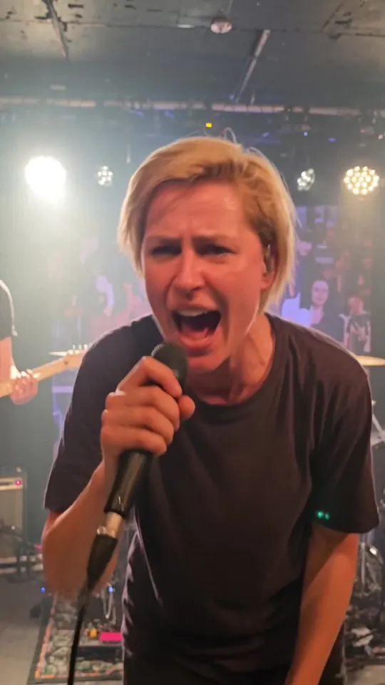 Kadr z filmu AI: Mały klub, światła sceny i tłum pod barierkami.